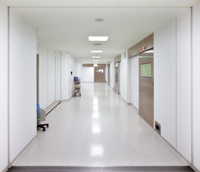 Long empty hospital surgery corridor with lamps turned on