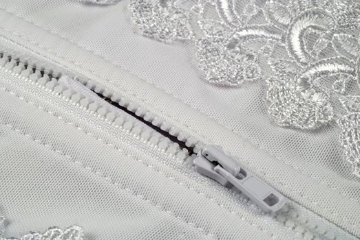 picture of a zipper in a white and laced girdle