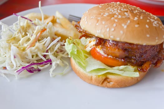 Chicken burger with tomato cucumber lettuce on white dish