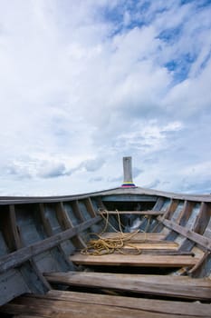 Nose of empty wooden boat on the sky background 