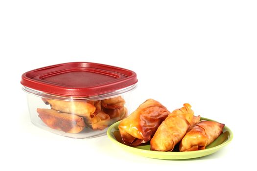 Pancakes with meat in a plate and a plastic box for storage of products.