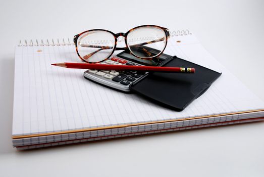 Pictures of a calculator and glasses resting on a notepad, ready to do calculations