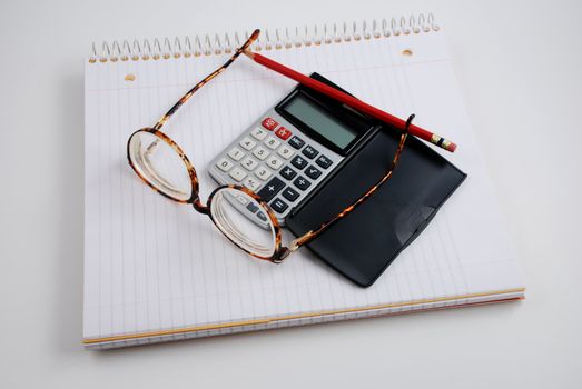 Pictures of a calculator and glasses resting on a notepad, ready to do calculations