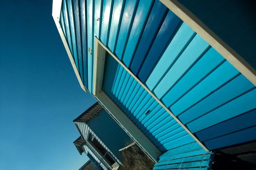 A Colourful Blue photo of a Row of Beach Huts on a Sunny Summers Day