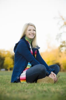 Portrait of a Pretty Blond Teen Girl Sitting  in a Park
