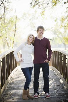 Portrait of a Brother and Sister Standing on a Bridge in a Park