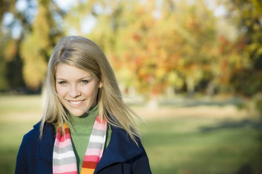 Portrait of a Pretty Blond Teen Girl Standing in a Park With Hair Blowing
