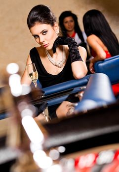 Beautiful elegant female with black gloves sitting behind roulette table
