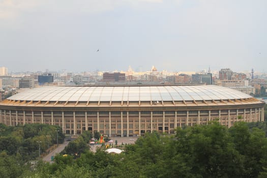 view of the stadium "Luzhniki" against the backdrop of the urban landscape in summer with clouds in the sky