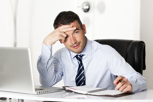 pensive man in office with computer and pen