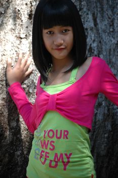 cute asian girl stand up beside tree in park