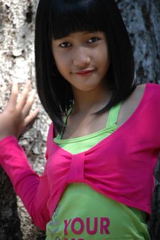 cute asian girl stand up beside tree in park