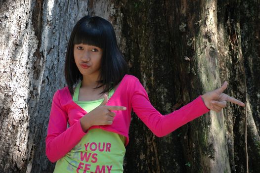 cute asian girl stand up beside tree in park