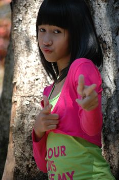 cute asian girl stand up beside tree in park