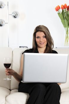 beautiful woman on sofa with computer and glass of wine