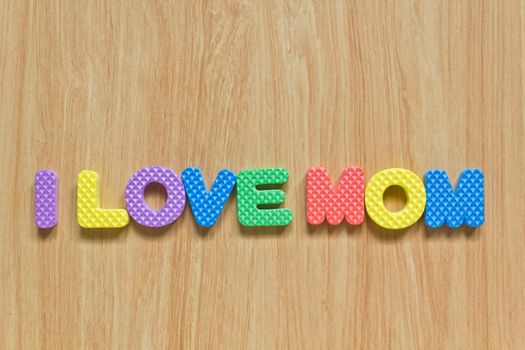 colorful letters with "I love mom" isolated on wood texture