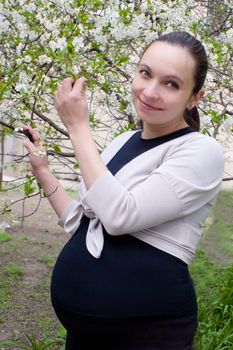 Smiling pregnant woman in blooming garden