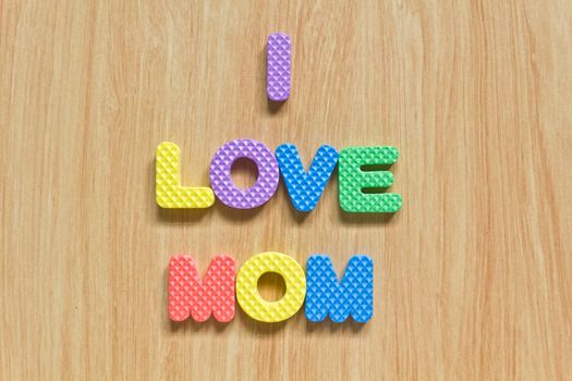 colorful letters with "I love mom" isolated on wood texture