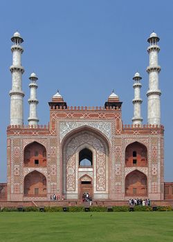 White marble decorations on red sandstone over green lawn against blue skies.