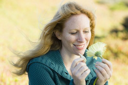 Portrait of a Pretty Redhead Woman Looking at a Flower