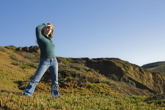 Portrait of a Pretty Redhead Woman On Cliff Shielding Her Eyes