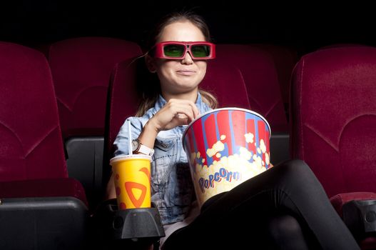 young woman sitting alone in the cinema and watching a movie