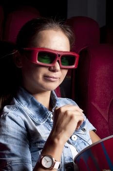 young woman sitting alone in the cinema and watching a movie