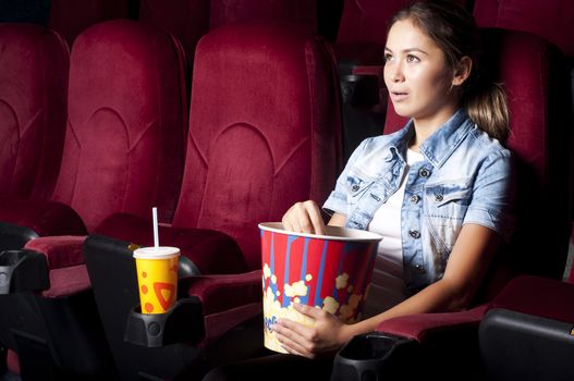 young woman sitting alone in the cinema and watching a movie