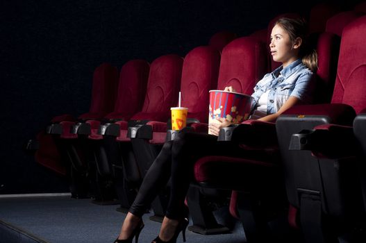 young woman sitting alone in the cinema and watching a movie