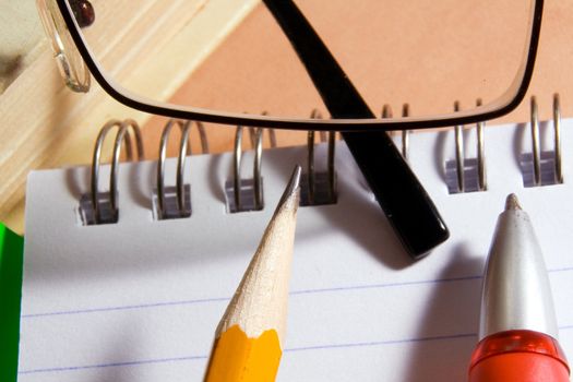 Notebook for notes, the book, the pen, a pencil, glasses on a desktop