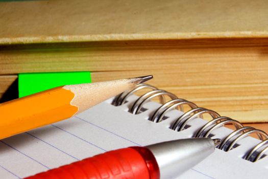 Notebook for notes, the book, the pen, a pencil on a desktop