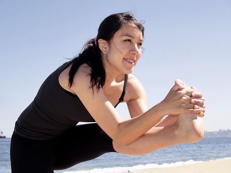 Yoga teacher practising at the beach pose dandayamana janushirasana