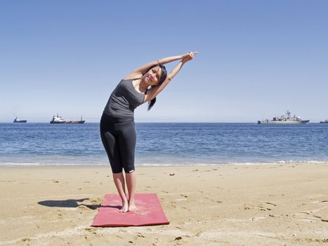 Yoga teacher practising at the beach pose arda chandrasana