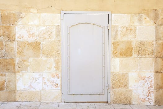 Structure of the weathered stone bricks wall, with painted gray iron door