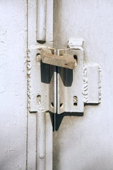 Old iron door painted in grey colour closed on the padlock