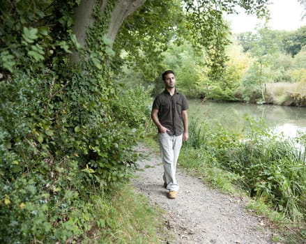 Man walking along a canal path.