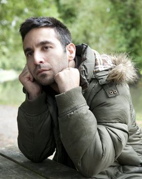 Man looking pensive, sitting by a canal.