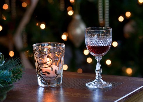 Glass of sherry or port in front of out of focus christmas tree and lit by a candle