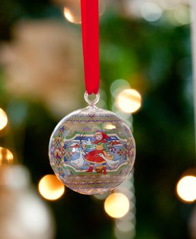 Hand painted glass ornament in front of out of focus tree