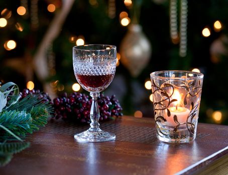 Cut glass sherry or port in front of xmas tree with cranberries and lit by candle