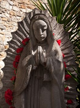 Virgin Mary Statue with red blossoms near a Mission in San Antonio in Texas