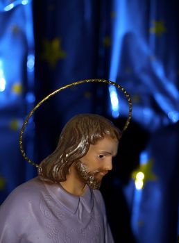 Traditional statuette of St. Jospeh looking down on the scene of the Nativity    