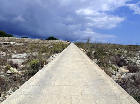 Lone countryside uphill path in Malta, seemingly leading to the skies into nowhere