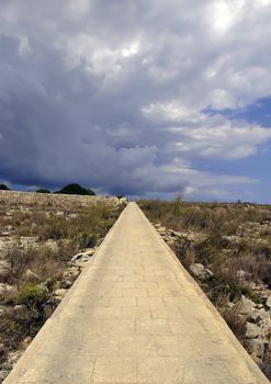 Lone countryside uphill path in Malta, seemingly leading to the skies into nowhere