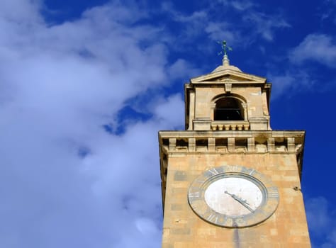 A medieval clocktower against blue sky and clouds