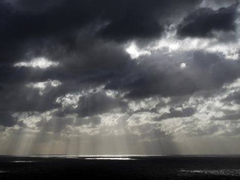 Clouds looming over the horizon with rays seeping through cast