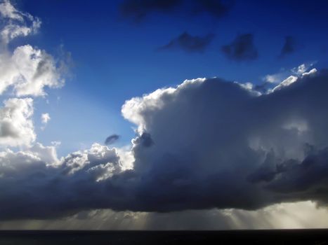 Clouds looming over the horizon with rays seeping through cast