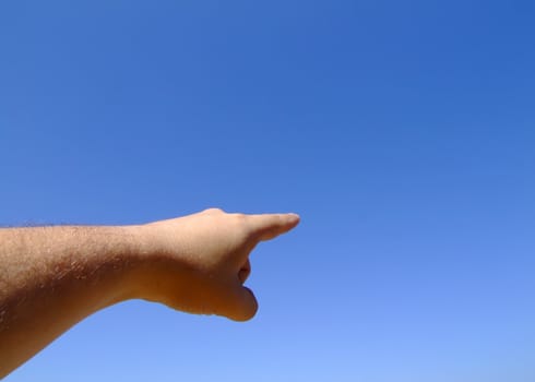 Hand pointing towards blank copyspace in the clear blue sky