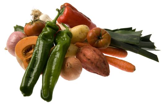 A group of green and red peppers, pumpkin, sweet potatoes, tomatoes, onions, potatoes and leeks isolated against white.