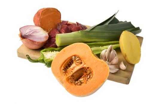 Vegetables arranged over a wooden chopping board, isolated against a white background.